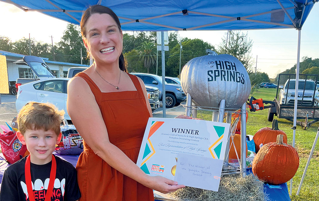 Photo special to Alachua County Today / High /Springs CRA's Amy Bohanon, accompanied by son Hudson, as she displays the award for STEAK OUT, winning pumpkin that Most Represented High Springs