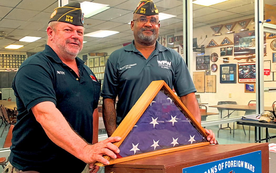 Photo by MICHAEL P. MAUER special to Alachua County Today / Alachua County Veterans of Foreign Wars Post 2811 Quartermaster Avery Owen, left, and Commander Chester Lundy display the flag that was rescued and returned to the Gainesville post after being thrown away in a dumpster 350 miles away.