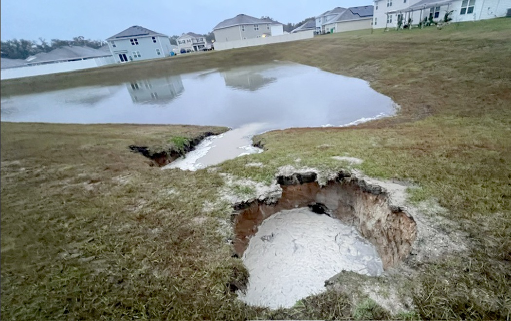Photo special to Alachua County Today / Water quickly fills sinkhole that opened up in Oak Ridge. High Springs Building Department notified, area taped off.